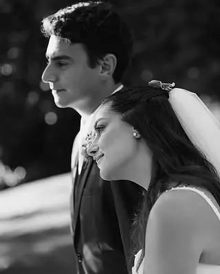 Retrato em preto e branco do casal de perfil, a noiva apoiada no ombro do noivo, de olhos fechados e sorrindo