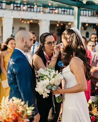 No altar, a cerimonialista seca com um lenço a lágrima da noiva, ao lado do noivo